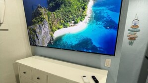 A flat-screen TV mounted on a wall, a white dresser below, and a small remote on the dresser. - Coastal Luxury - 5 min to beach (Fort Lauderdale)