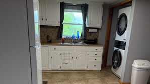 A kitchen with white cabinets, a built-in washing machine, and a tiled floor.