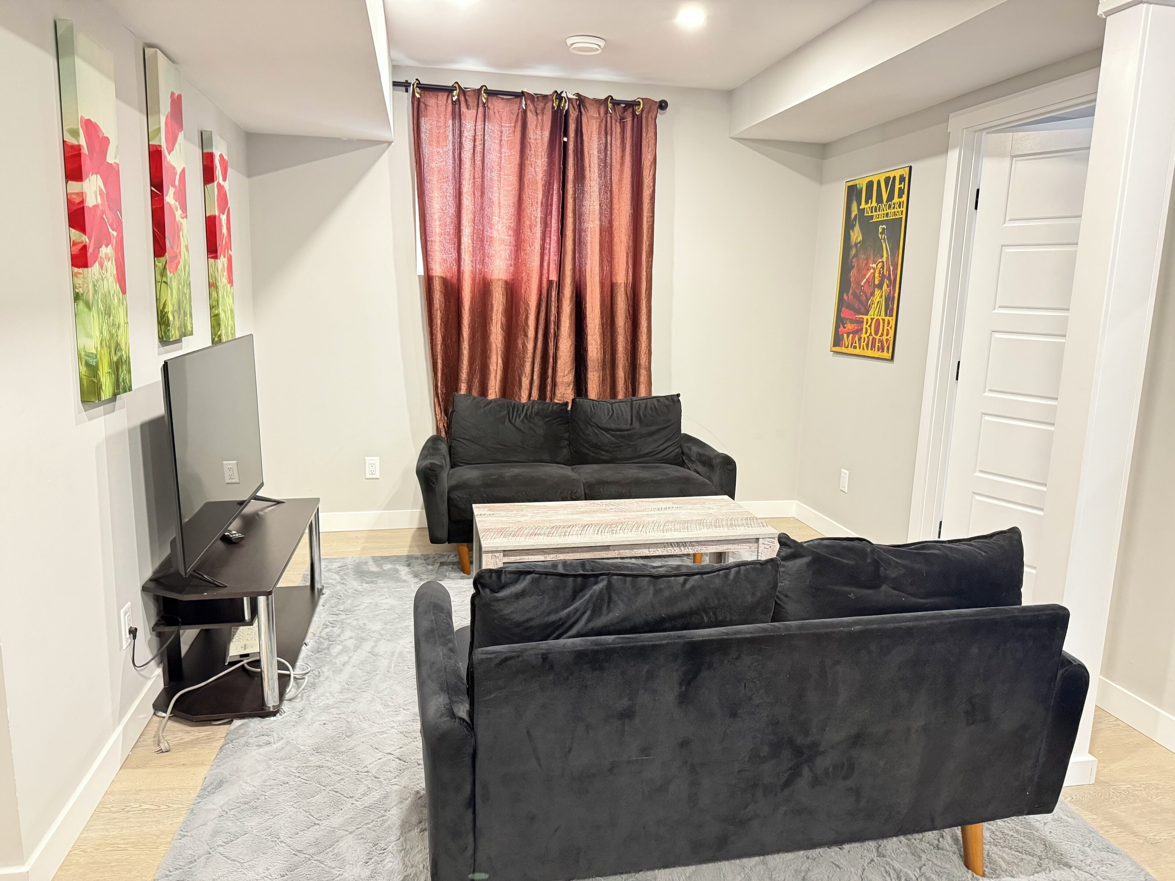 A modern living room with a black sofa, a flat-screen TV, and a coffee table.