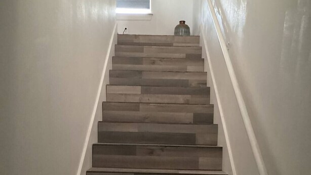 Una escalera con escalones de madera y paredes blancas.