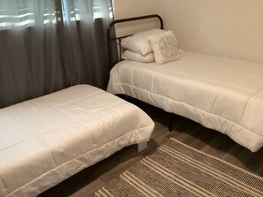 Two single beds with white mattresses and duvets, set in a cozy space.