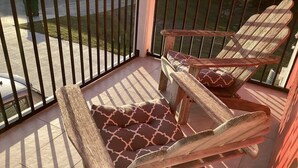Dos sillas de madera con cojines estampados en un balcón con baranda de metal.