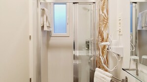 A modern bathroom with a glass shower enclosure, a large white bathtub, and a marble-patterned wall. - Bilbao ROOMS Etxebarria (Bilbao)