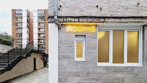 A building with a 'ROOMS' sign, a window with frosted glass, and a staircase leading to a door. - Bilbao ROOMS Etxebarria (Bilbao)