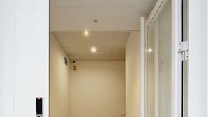 A narrow hallway with wooden flooring, a door with a glass panel, and a wall-mounted intercom. - Bilbao ROOMS Etxebarria (Bilbao)