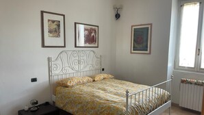 A bedroom with a bed, a nightstand, a wall-mounted lamp, and framed artwork. - BeB Cascina Mentirone (Rosate)