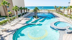 Une piscine de forme circulaire, entourée de chaises longues et de palmiers, offrant une vue sur la plage et l’océan.
