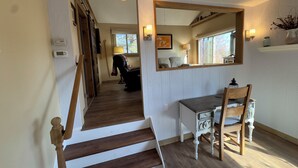 A staircase leading to a living area with a desk and chair, a mirror, and a window.