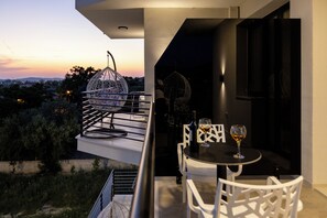 A balcony with a dining table and chairs, a hanging light fixture, and a view of the sunset. - Zani's Villa (Vlorë)