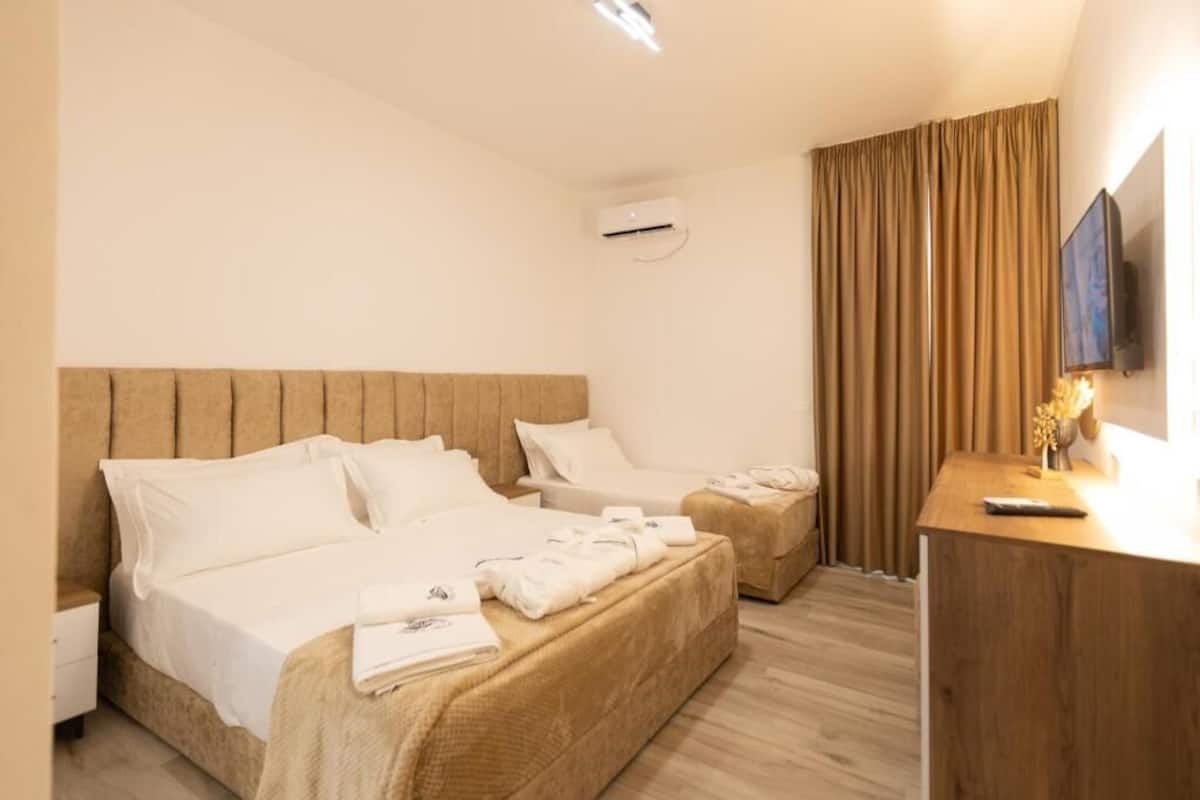 Hotellihuone, jossa on kaksi sänkyä, puinen pääty ja työpöytä sekä televisio.