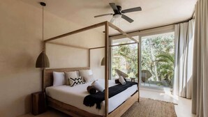 Une chambre à coucher avec un lit à baldaquin en bois, un ventilateur de plafond et une vue sur la verdure environnante.