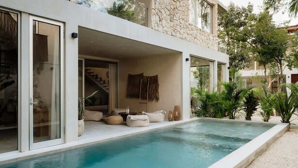 Une maison moderne dotée d’une piscine, d’une façade en pierre et d’un espace extérieur aménagé pour se détendre.
