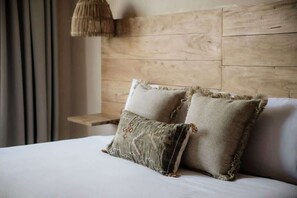 Un lit avec deux oreillers, une tĂȘte de lit en bois et un luminaire suspendu.