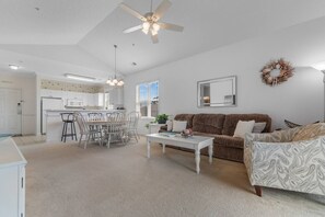 A spacious living area with a brown sofa, a white coffee table, and a dining table with chairs. - Stylish Barefoot Golf Condo with Pool Access (North Myrtle Beach)