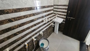 A bathroom with a marble wall, a sink, and a door. - Govind Resort (Mathura)