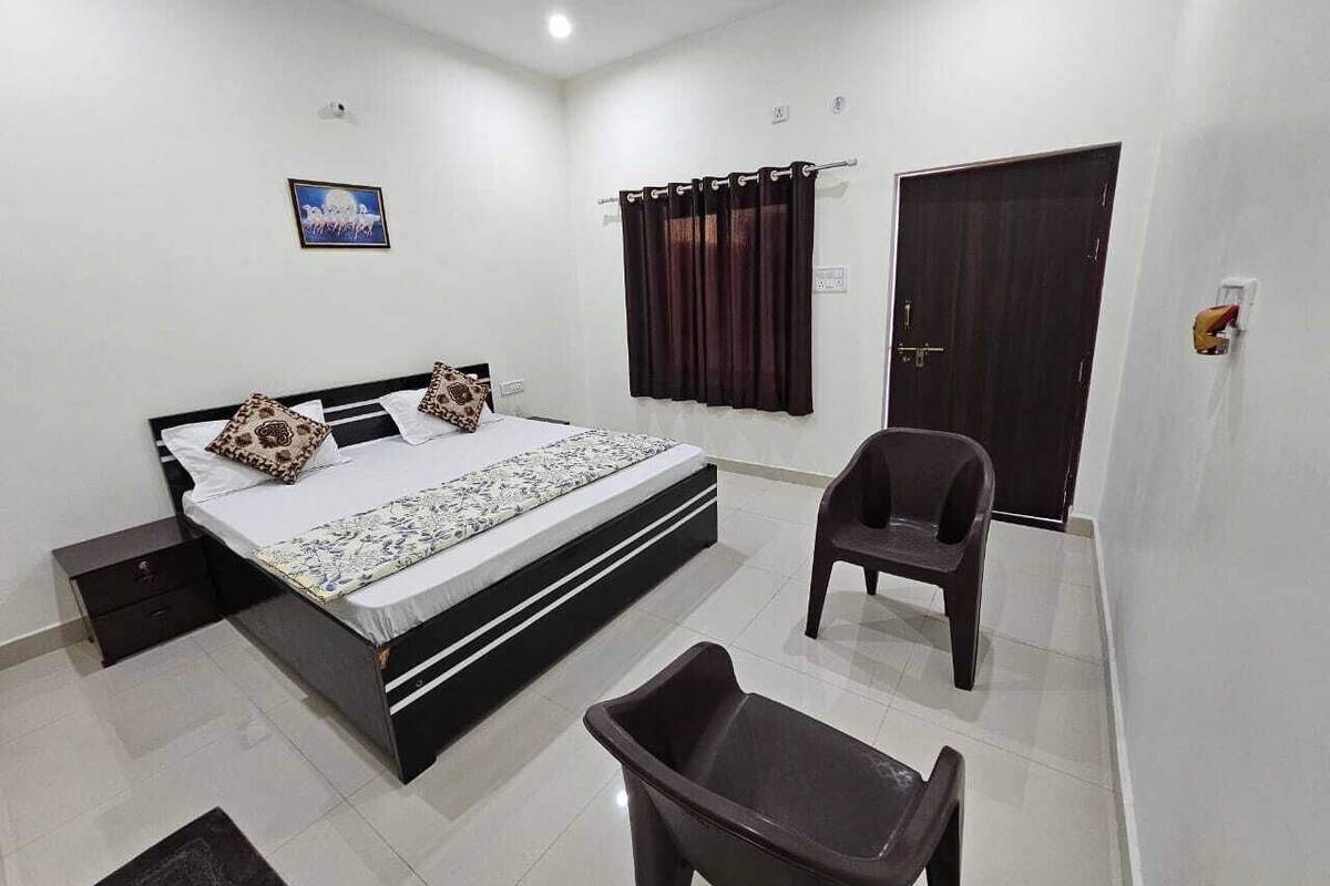 Une chambre à coucher avec un lit, une chaise, une petite table, une armoire et un tableau au mur.