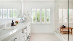 Un baño moderno con un espejo grande, tocador blanco y cabina de ducha de vidrio.