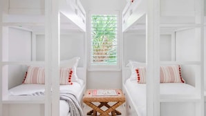 Habitación compacta con dos camas, una mesita pequeña y un ventanal con persianas.