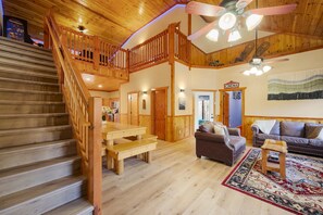 A spacious living area with a wooden staircase, a sofa, a coffee table, and a ceiling fan. - Pet friendly! Private heated pool! Theatre! (Cosby)
