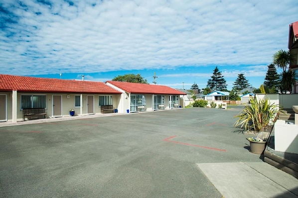 A row of motel buildings with red roofs, a parking lot, and some greenery. - Ahikaa Gisborne Motel (Gisborne)