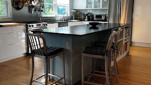 A modern kitchen with a large island, stainless steel appliances, and a view of the outdoors. - Historic 3-bedroom home in beautiful Athens. Walkable to town and Campus. (Athens)