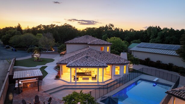 Une maison avec une piscine, un espace extérieur aménagé pour s’asseoir et une terrasse couverte.