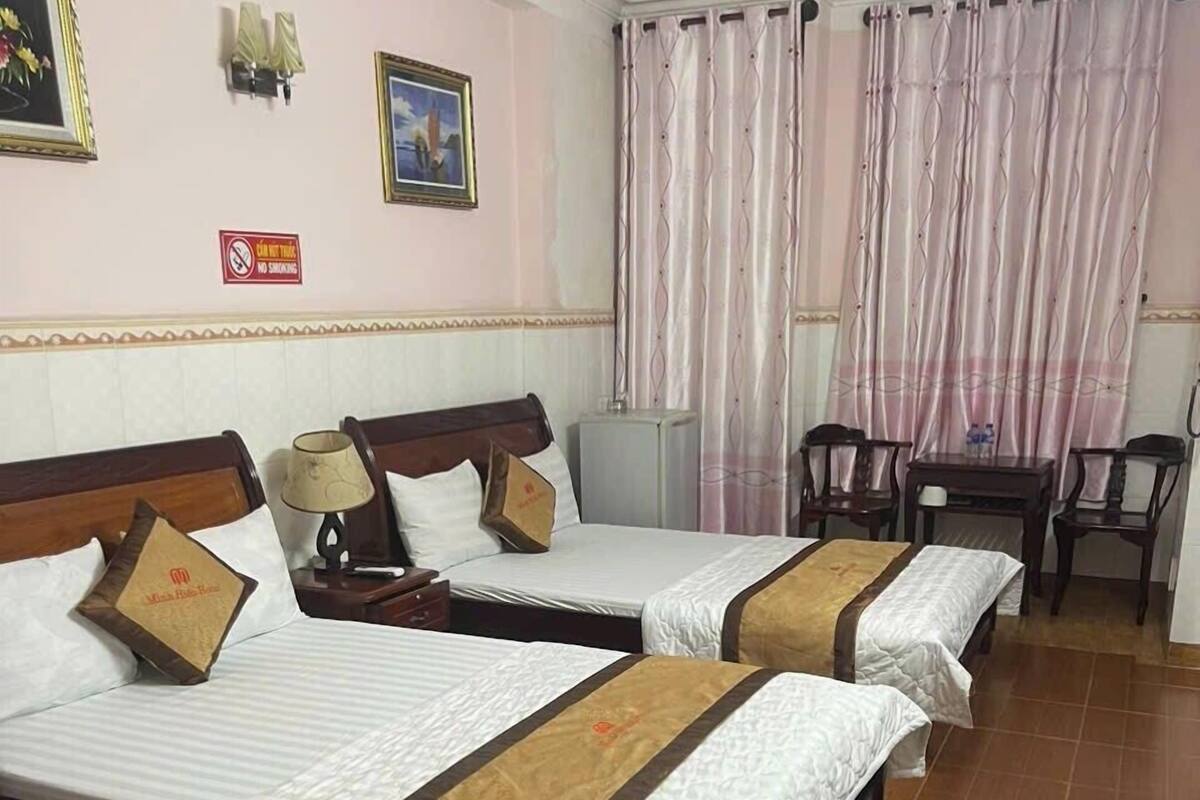 Une chambre d’hôtel avec deux lits, un bureau, une chaise et une petite table.