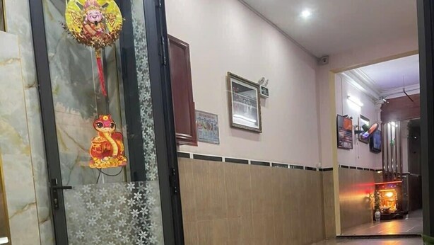 Una hall d'albergo con pavimento decorato, una porta in vetro con elementi ornamentali e un muro in legno con un quadro incorniciato.