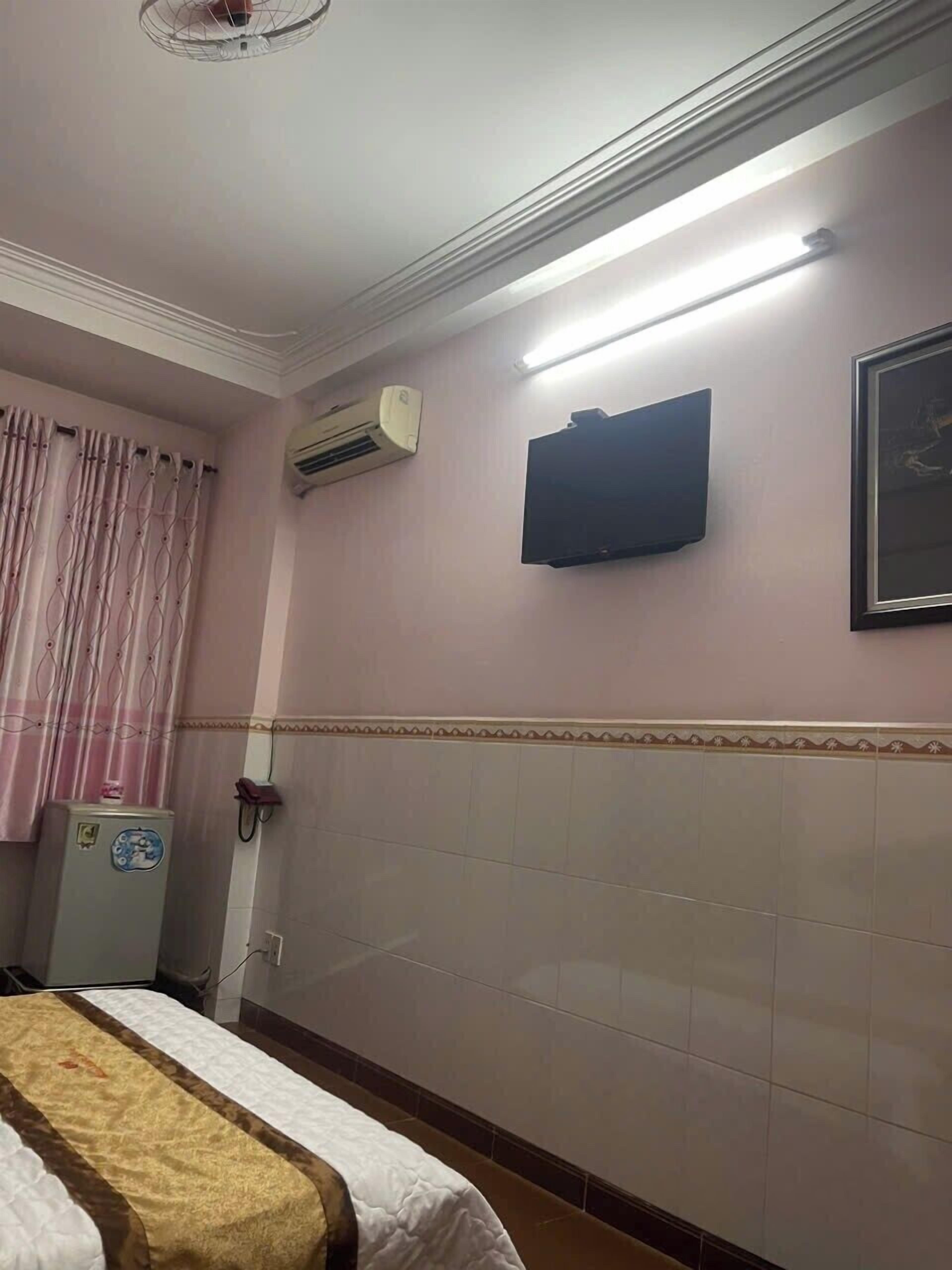 Una camera d'albergo con un letto, un climatizzatore, una TV a schermo piatto e un telefono fissato al muro.