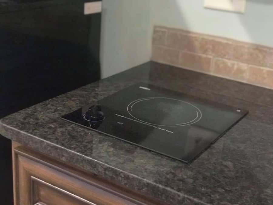 Een keuken met een geïntegreerde inductiekookplaat op een granieten aanrecht.