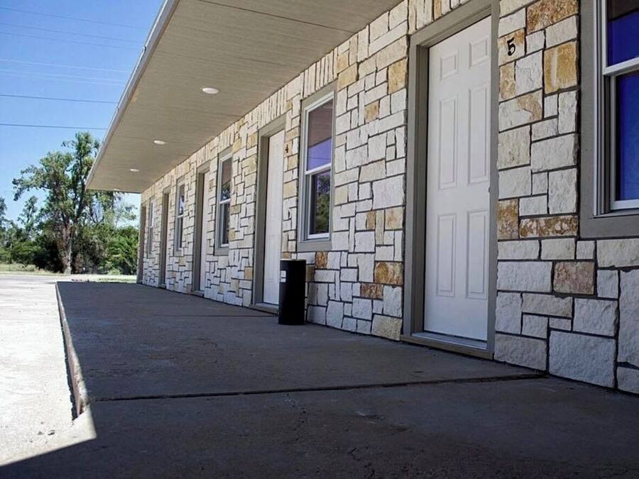 A building with a stone facade, numbered 5, featuring a covered entrance and multiple windows.