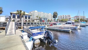 A marina with boats docked, a pedestrian bridge, and a large hotel building in the background. - Beautiful Barefoot Golf Resort Condo (North Myrtle Beach)