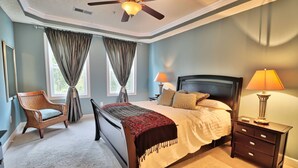 A bedroom with a bed, nightstands, a chair, and a ceiling fan. - Beautiful Barefoot Golf Resort Condo (North Myrtle Beach)