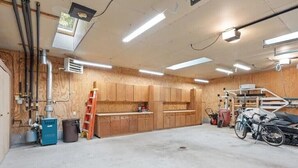 A garage with wooden cabinets, a workbench, and a bicycle. - 3-bedroom cabin + authentic log cabin that sleeps an additional 4-6 people !! (Crosslake)