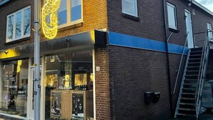 A two-story building with a storefront featuring a large illuminated sign. - Holidayhome De Molen (Noordwijk)