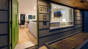 A modern house with a green door, a number 2713 on the wall, and a view of the interior through a large window. - Luxury Spa, Patio, Deck & Views of Puget Sound in the Heart of Old Town, Tacoma (Tacoma)