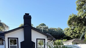 Un edificio moderno con un camino nero, pareti bianche e due finestre.