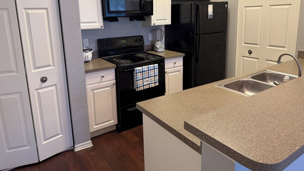 A kitchen with white cabinets, a black stove, a black refrigerator, and a granite countertop. - Cozy 1-bedroom with AC, WiFi in charming Plant City (Plant City)