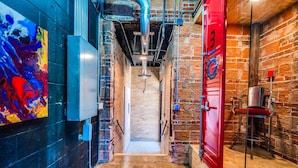 A narrow hallway with exposed brick walls, a red door, and a metal staircase. - b3 Room4: Begin King Suite (Sparta)