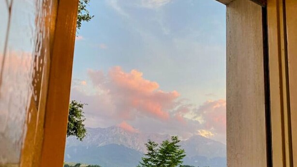 A window with a view of a mountainous landscape and greenery.