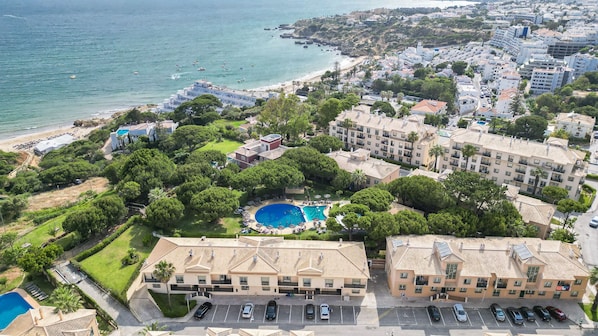 Zona residencial costera con piscina rodeada de vegetación, junto a una playa.