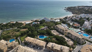 Zona residencial costera con varios edificios, una playa y una piscina grande.