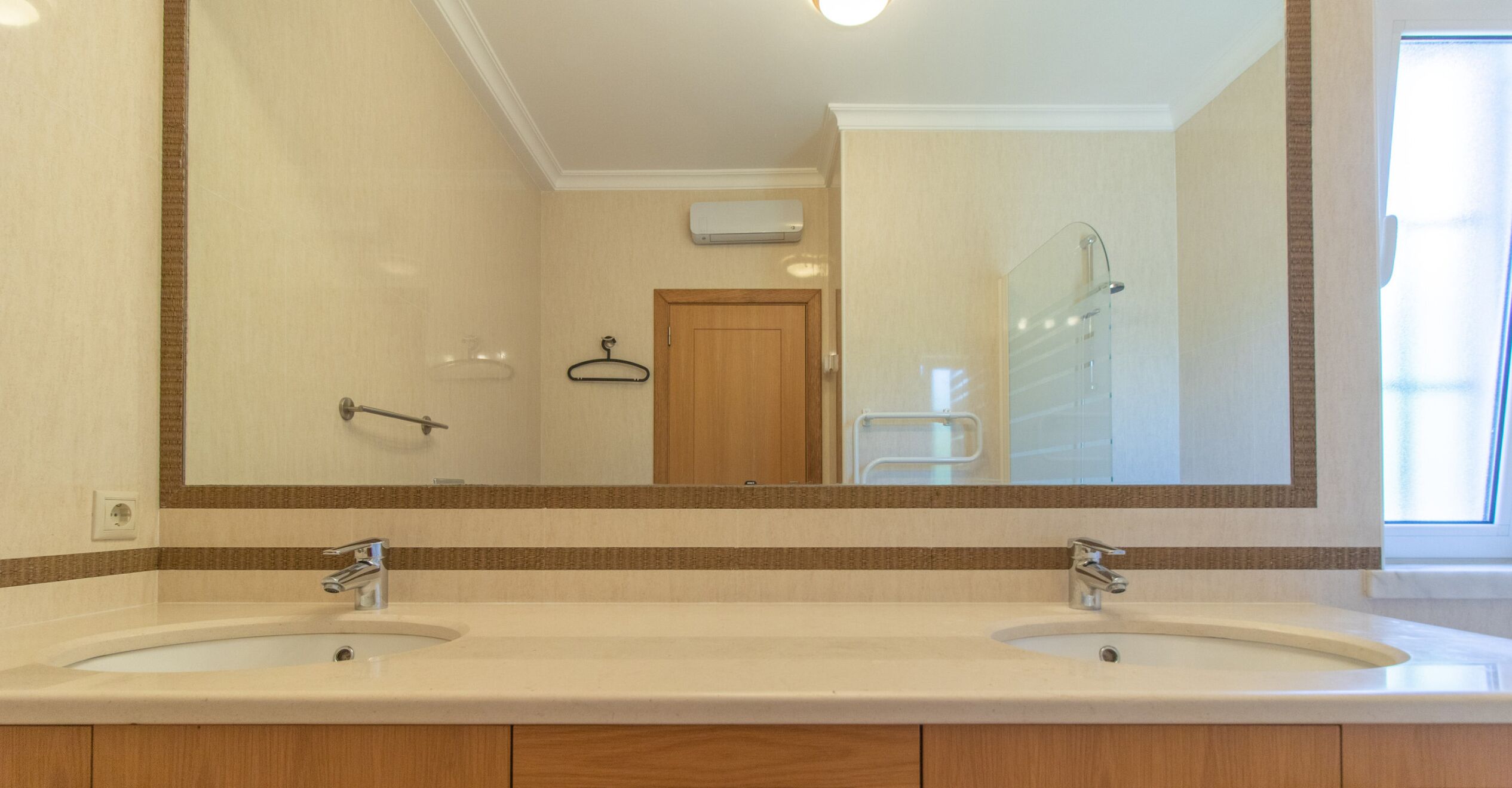 A bathroom with two sinks, a large mirror, and a shower.