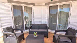 Un espace patio aménagé avec des meubles en osier, notamment un canapé et des fauteuils, ainsi qu’une petite table agrémentée d’un objet décoratif.