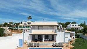 Une villa moderne dotée d’une piscine, d’un espace salon extérieur et d’un escalier menant à une terrasse sur le toit.