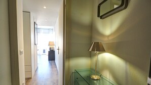 A hallway with a glass display case containing a lamp and a handbag. - Chic Sea View Apartment by Hello Homes Sitges (Sitges)