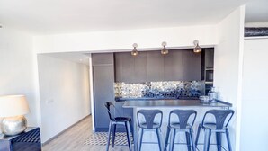 A modern kitchen with a central island, bar stools, and pendant lighting. - Chic Sea View Apartment by Hello Homes Sitges (Sitges)