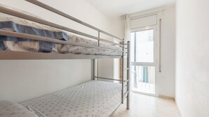 Een slaapkamer met stapelbed, raam en deur.