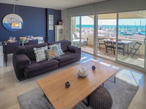 Un salon moderne avec un canapé, une table basse et une vue sur un port de plaisance.