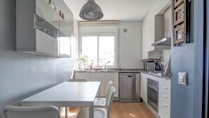 Une cuisine compacte comprenant un coin repas, un lave-vaisselle, une cuisinière et une fenêtre laissant entrer la lumière naturelle.